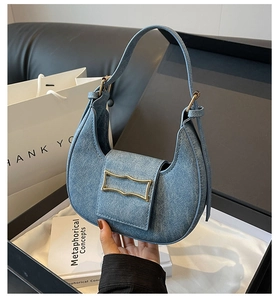 Détail du sac croissant en denim bleu avec fermoir doré et bandoulière ajustable