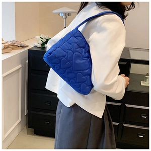 Detail der blauen Schultertasche mit Herzsteppung und eleganter Trapezform für Damen