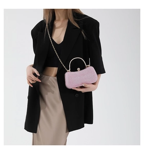 Detail of pink glitter evening clutch with golden metal handle and diamond-encrusted buckle