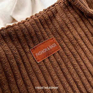 Detailed macro view of the brown corduroy fabric texture and premium leather logo patch