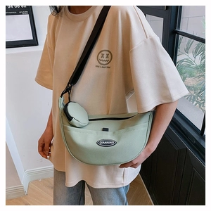 Pale green nylon crescent crossbody bag with mini pouch on black adjustable strap