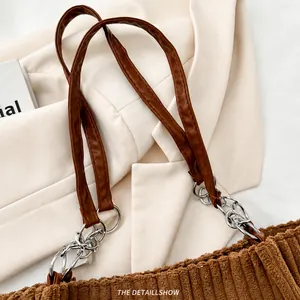 Close-up of brown corduroy tote bag featuring leather handles and silver metal hardware