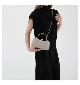 Detail of sequined evening clutch with curved metal handle and detachable gold chain strap