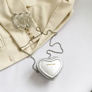 Détail du mini sac argenté en forme de cœur avec bandoulière en chaîne métal