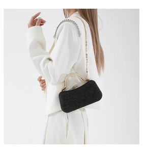 Detail of elegant black glitter evening clutch with gold handle and chain on model
