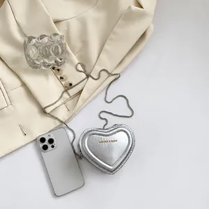 Mini sac argenté en forme de cœur avec chaîne et téléphone pour comparer la taille