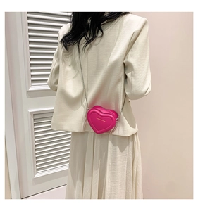 Detail of pink heart-shaped crossbody bag with silver chain and fashion logo