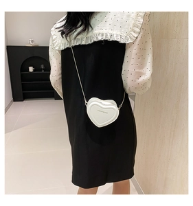Close-up of a white heart-shaped mini crossbody bag with Fashion & Bags lettering print