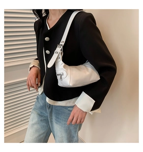 Close-up of a white leather underarm bag with adjustable strap worn by a model