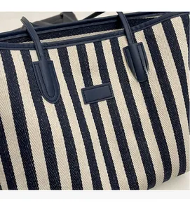 Detail van blauw-wit gestreepte canvas shopper met geweven textuur en leren handvat