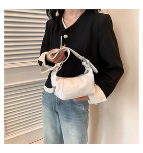 Close-up of white leather handbag with adjustable silver eyelets and metal zipper