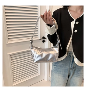 Detail of silver metallic underarm bag with adjustable strap shown on model's shoulder