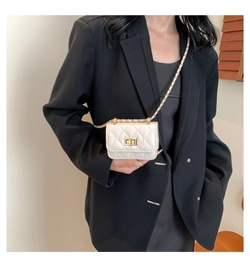 Nahaufnahme der gesteppten weißen Mini-Umhängetasche mit goldener Kette auf schwarzem Blazer