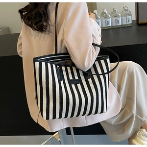 Detailweergave van de grote gestreepte canvas shopper met zwarte bandjes en lederen accent