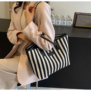 Detail van een grote gestreepte canvas shopper vastgehouden door een gekleed model