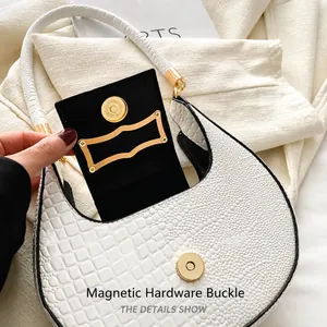 Détail du fermoir magnétique doré sur un sac demi-lune blanc avec texture en relief