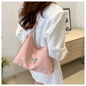 Dettaglio borsa hobo rosa metallizzata con ciondolo a farfalla e tracolla a catena