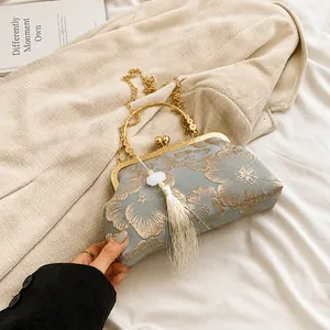 Detailed shot of vintage blue satin evening bag with gold floral embroidery and tassel