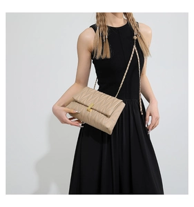 Detail of beige quilted crossbody bag featuring elegant gold clasp and chain strap