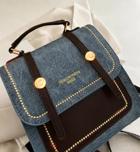 Detail view of denim and brown leather patchwork with gold rivets and brand logo