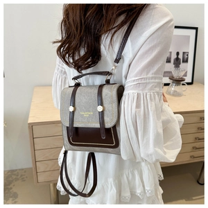 Detail of vintage grey satchel backpack featuring brown leather trim and metallic buckle