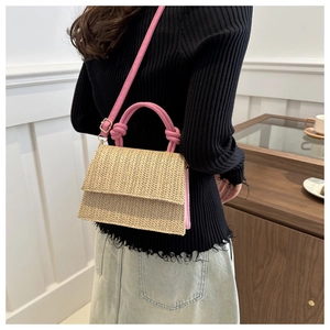 Détail d'un sac bandoulière en paille tressée avec bandoulière et poignée nouée rose