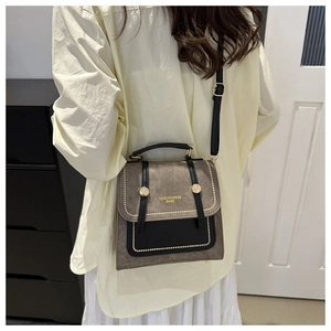 Detail van vintage crossbodytas met grijs suède, zwart leer en gouden studs