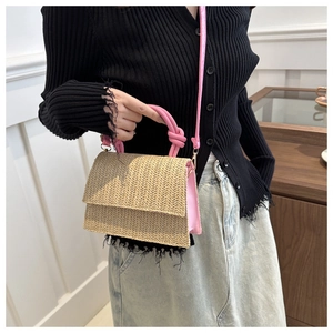 Vue détaillée du sac en paille tressée avec bordure en similicuir rose et poignée nouée