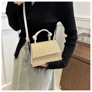 Détail du sac bandoulière en paille tressée avec poignée en cuir blanc et métal doré