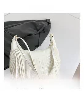 Détail d'un sac en cuir blanc grainé avec boucles dorées et longues franges de côté