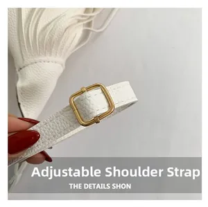 Détail de la bandoulière réglable en cuir blanc avec boucle dorée sur le sac à main