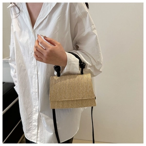 Détail du sac bandoulière en paille tressée avec texture en V et poignée noire torsadée