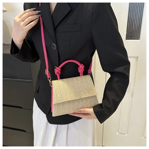 Détail du sac bandoulière tressé avec poignée rose et motif texturé à chevrons