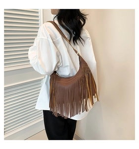 Sac Hobo en cuir marron avec de longues franges décoratives porté sur l'épaule