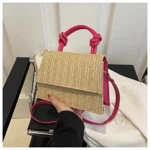 Détail du sac bandoulière en paille tissée avec garniture en cuir rose et poignée nouée