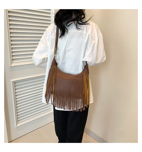 Sac hobo marron à franges porté par le mannequin pour un look bohème vintage