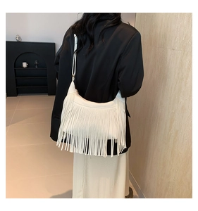 Gros plan d'un sac à bandoulière blanc à longues franges porté par un mannequin chic