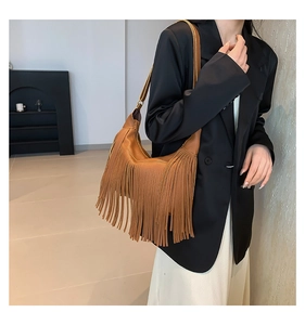 Détail montrant la texture des franges en cuir marron et le drapé du sac sur un modèle