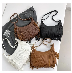 Détail de quatre sacs demi-lune à franges en noir, blanc, caramel et marron foncé