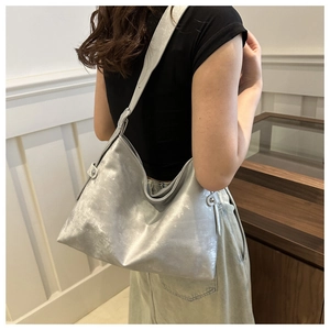 Side view of large silver tote bag with metallic finish shown on model's shoulder