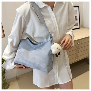 Detail of light blue tote bag with matte texture, silver chain, and cloud pendant