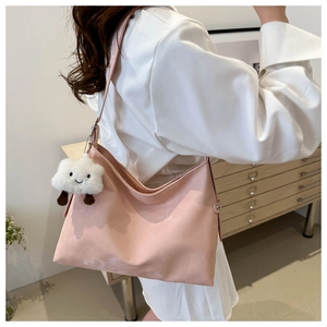 Pink tote bag with cute white cloud plush pendant worn by model in casual indoor setting