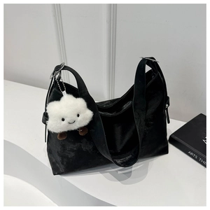 Detail of black velvet tote bag with white cloud plush pendant on a minimal white stand