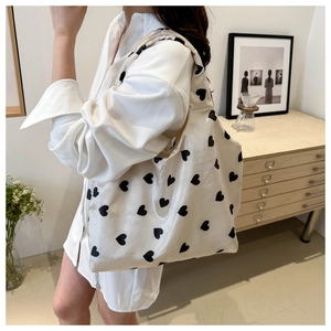 Close-up of white heart print canvas tote bag with silk texture held by model