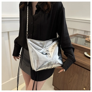 Detail of silver metallic bucket bag showing mirror-finish texture and chain strap