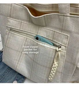 Close-up of front zipper pocket on beige canvas tote bag for small item storage
