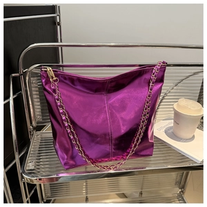 Detail of metallic purple tote bag with glossy finish and gold chain shoulder strap