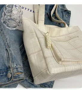 Detail of beige canvas tote with subtle plaid pattern and woven rope zipper pull