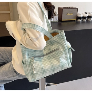 Detail of green checkered canvas tote bag with front zipper pocket and wide strap