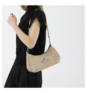 Détail d'un sac porté épaule beige Y2K avec clous argentés et logo étoile sur mannequin